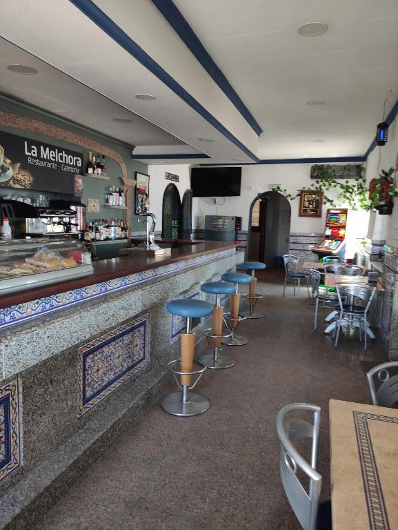 un restaurante con un bar con mesas y sillas en Hostal Restaurante Bar Cafeteria La Melchora, en Posadas