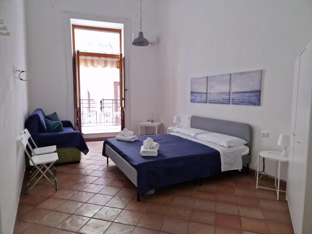 a bedroom with a bed and a chair and a window at Le Stanze di Marta in Cefalù