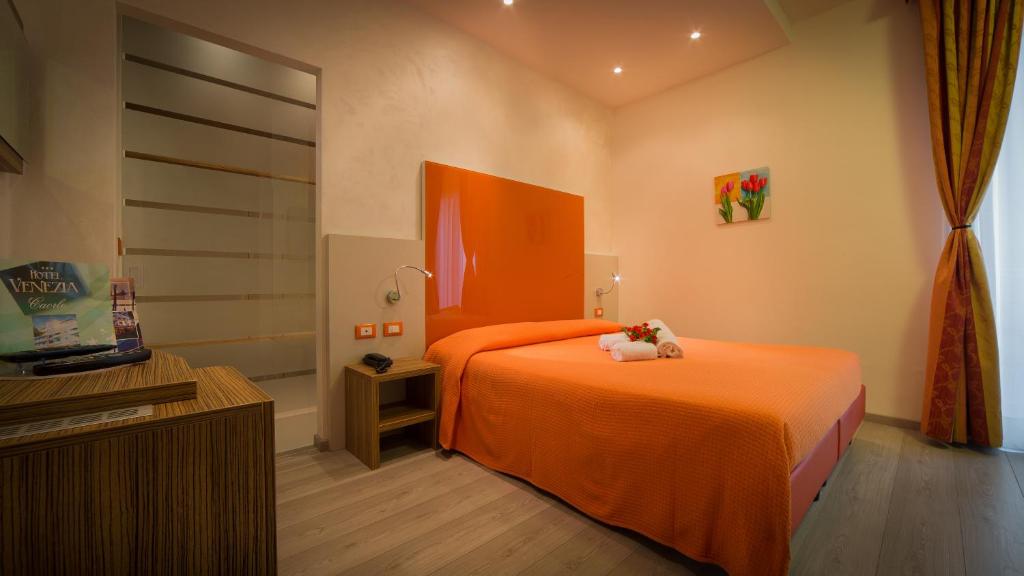 a bedroom with an orange bed with a teddy bear on it at Hotel Venezia in Caorle