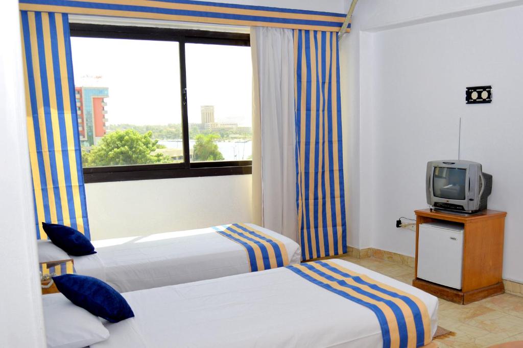 Habitación de hotel con 2 camas y TV en Marhaba Palace Hotel en Asuán