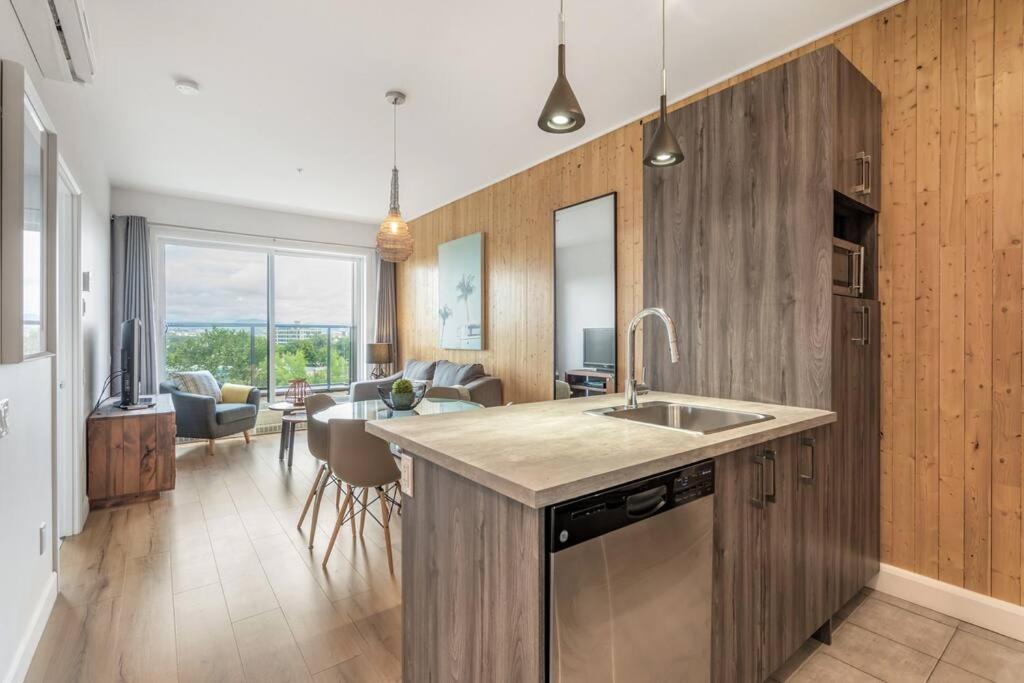 Hotel INITIAL / WAVE + Parking / Centre-Ville de Quebec, a kitchen with a sink and a living room at INITIAL / WAVE + Parking / Centre-Ville de Quebec in Quebec City