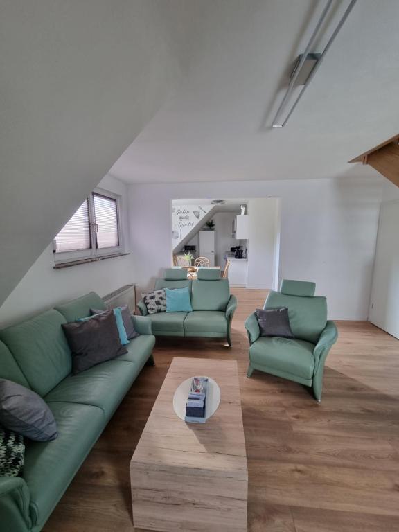 a living room with green couches and a table at Ferienwohnung bei Natie in Brilon