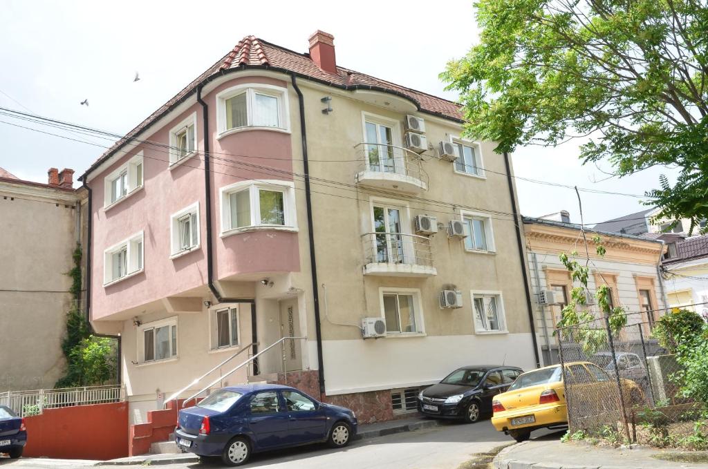 un edificio rosa con coches estacionados frente a él en City Center Apartments & Suites by RDC, en Bucarest