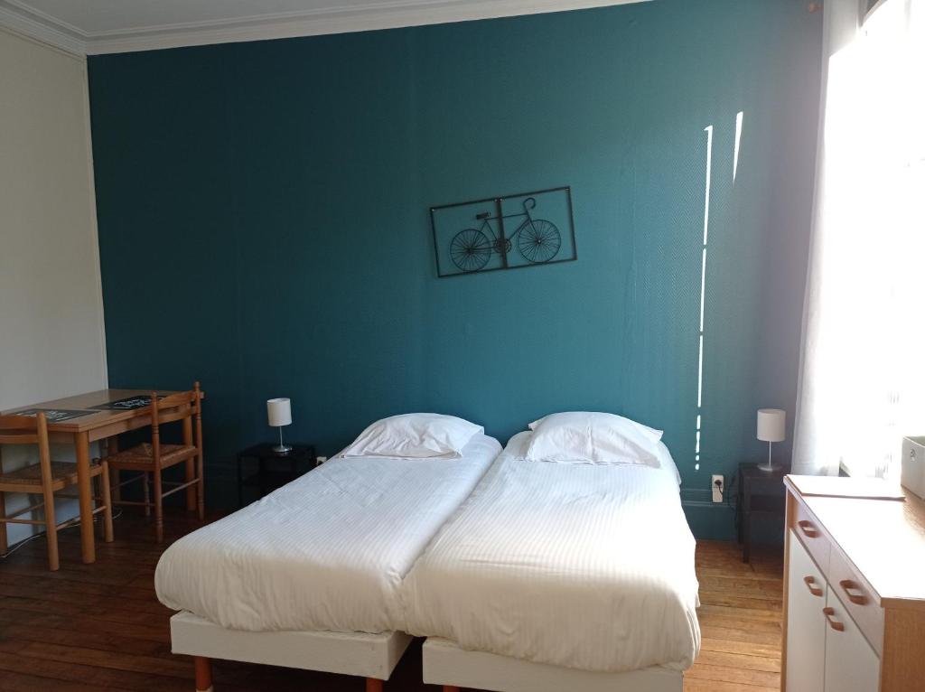 a bedroom with a bed and a blue wall at Le Nid - Studios in Chartres