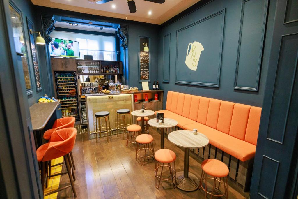 a restaurant with orange seats and tables and a bar at Vancouver Studios in London