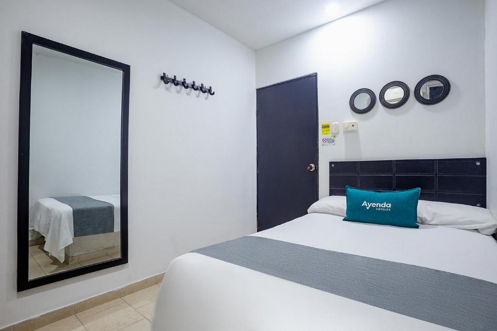 a bedroom with a large bed and a mirror at Ayenda Hotel Alejandría in Montería