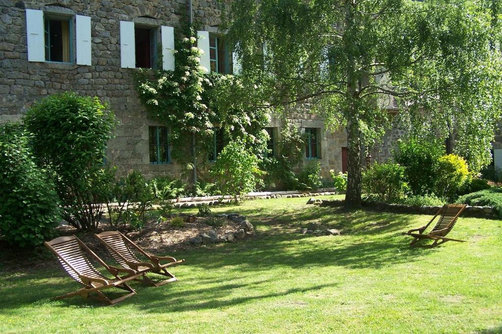 dos sillas de madera sentadas en el césped frente a un edificio en Domaine de Salomony, en Marcols-les-Eaux