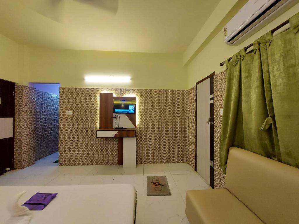 a bathroom with a couch and a shower with a mirror at Hindusthan Inn - On Beach in Mandarmoni