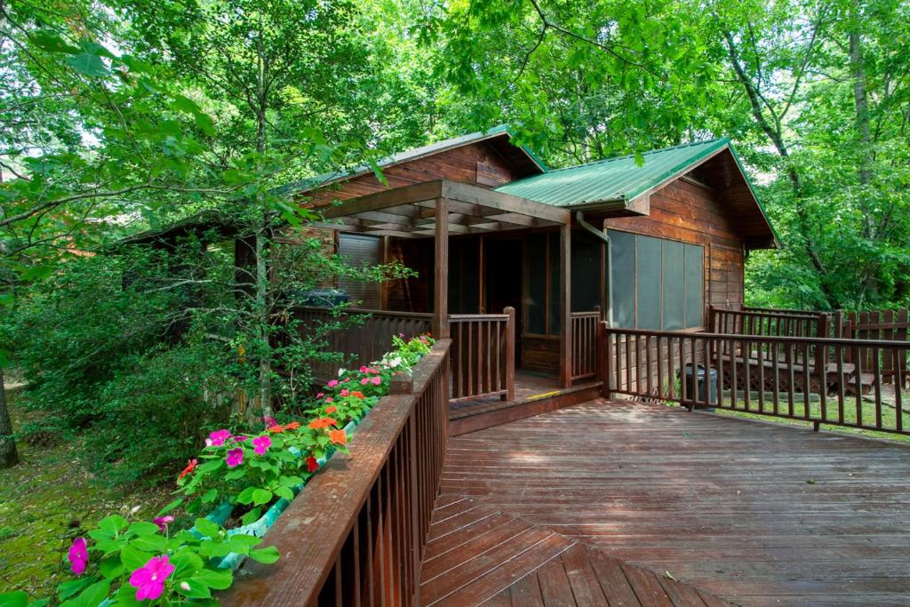 Cabaña pequeña con terraza de madera y flores en Highland Forest Cabins Duo Cabin Retreat, en Pigeon Forge