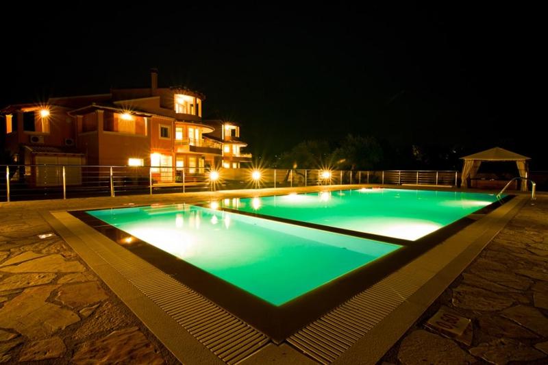 ein Schwimmbad in der Nacht mit einem Gebäude im Hintergrund in der Unterkunft Captain Alex Villa 2 in Dafnila