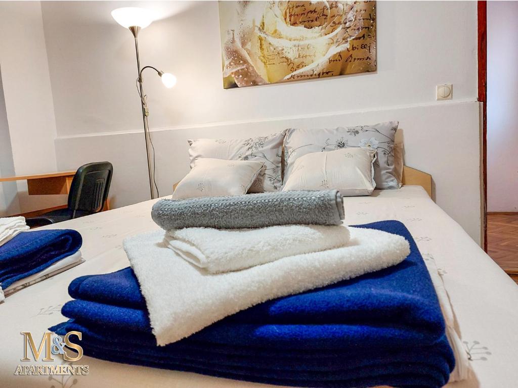 a bed with blue and white towels on it at Stefan Apartman in Novi Sad