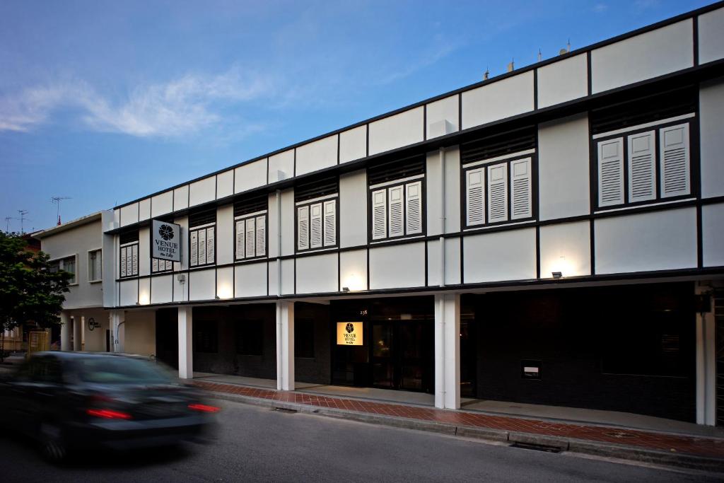 a car driving past a building on a street at Venue Hotel The Lily in Singapore