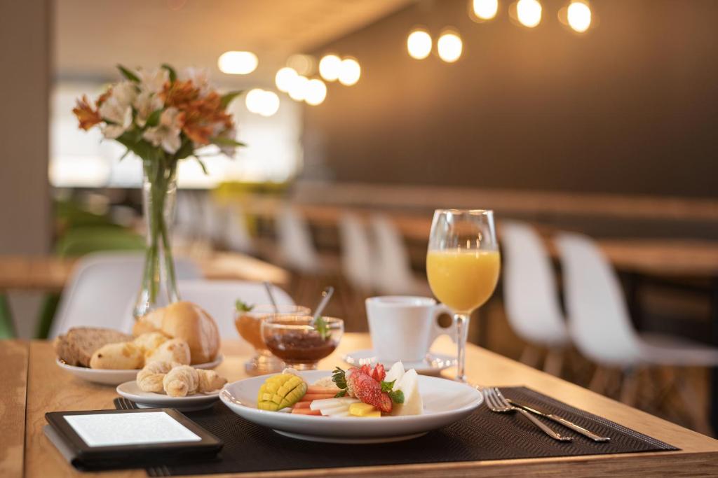 een tafel met borden en een glas sinaasappelsap bij Intercity Canoas in Canoas