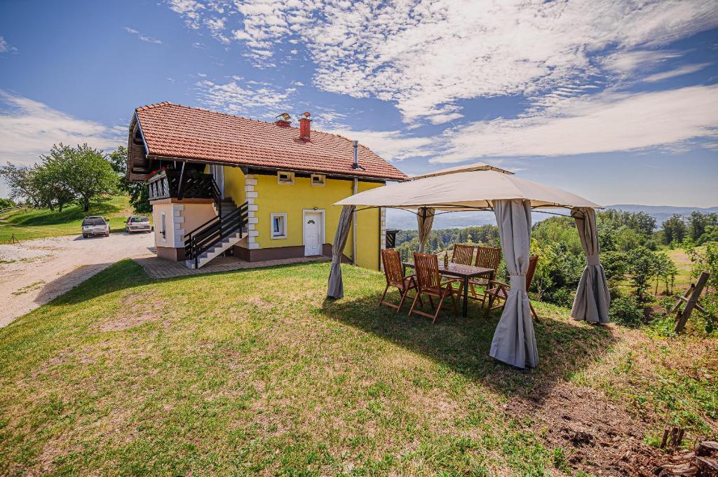 a table and chairs under an umbrella in front of a yellow house at Eko Pony Ranch Ogrizek in Podčetrtek