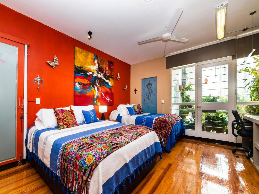 2 camas en una habitación con paredes de color naranja en Casa ITZAE B&B- Lincoln Park dog friendly, en Ciudad de México