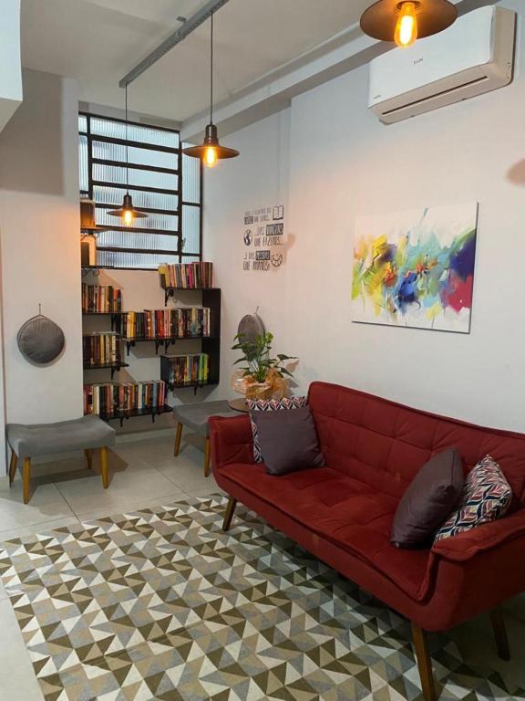 a living room with a red couch and a book shelf at HOSTEL CUARTO in Sao Paulo