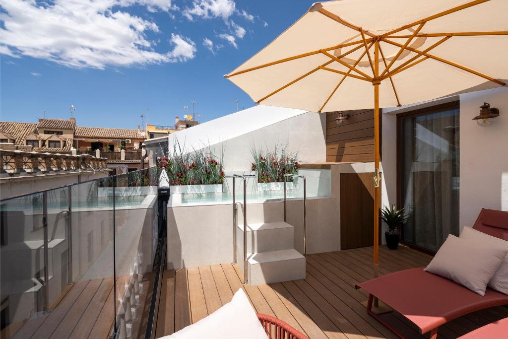 een patio met een parasol en een stoel op een balkon bij Palatina Concept Suites in Granada