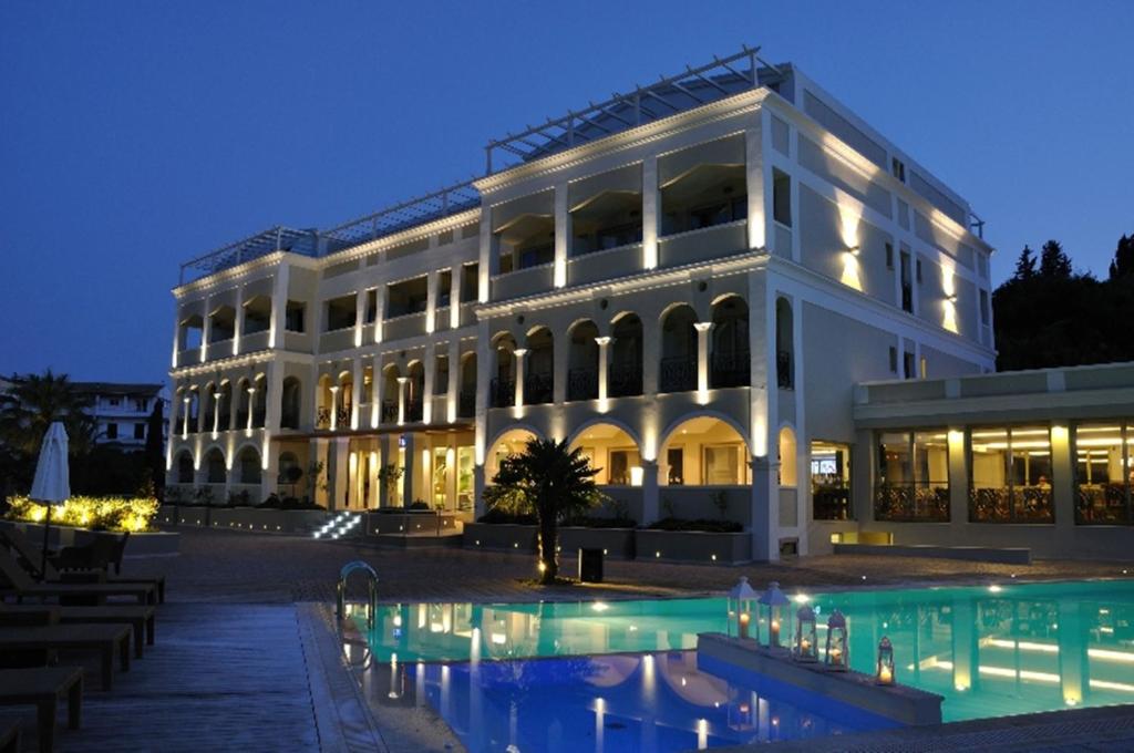 - un grand bâtiment blanc avec une piscine en face dans l'établissement Corfu Mare Hotel -Adults only, à Corfou
