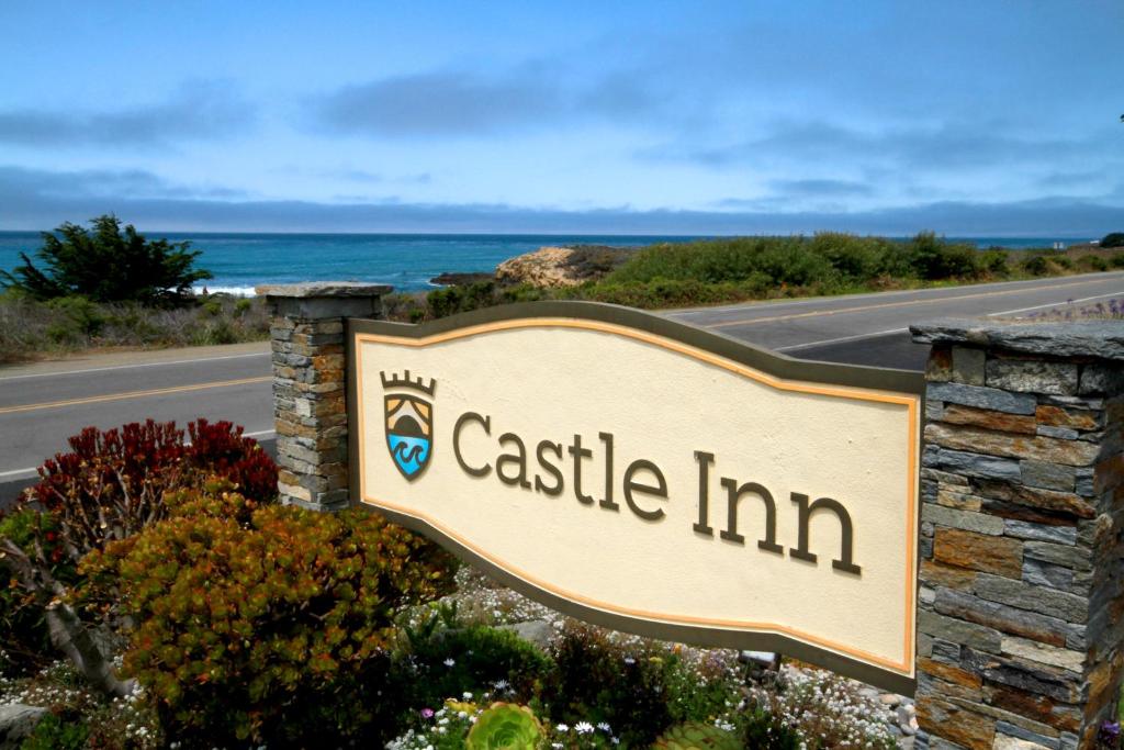 a sign for a castle inn with the ocean in the background at Castle Inn in Cambria