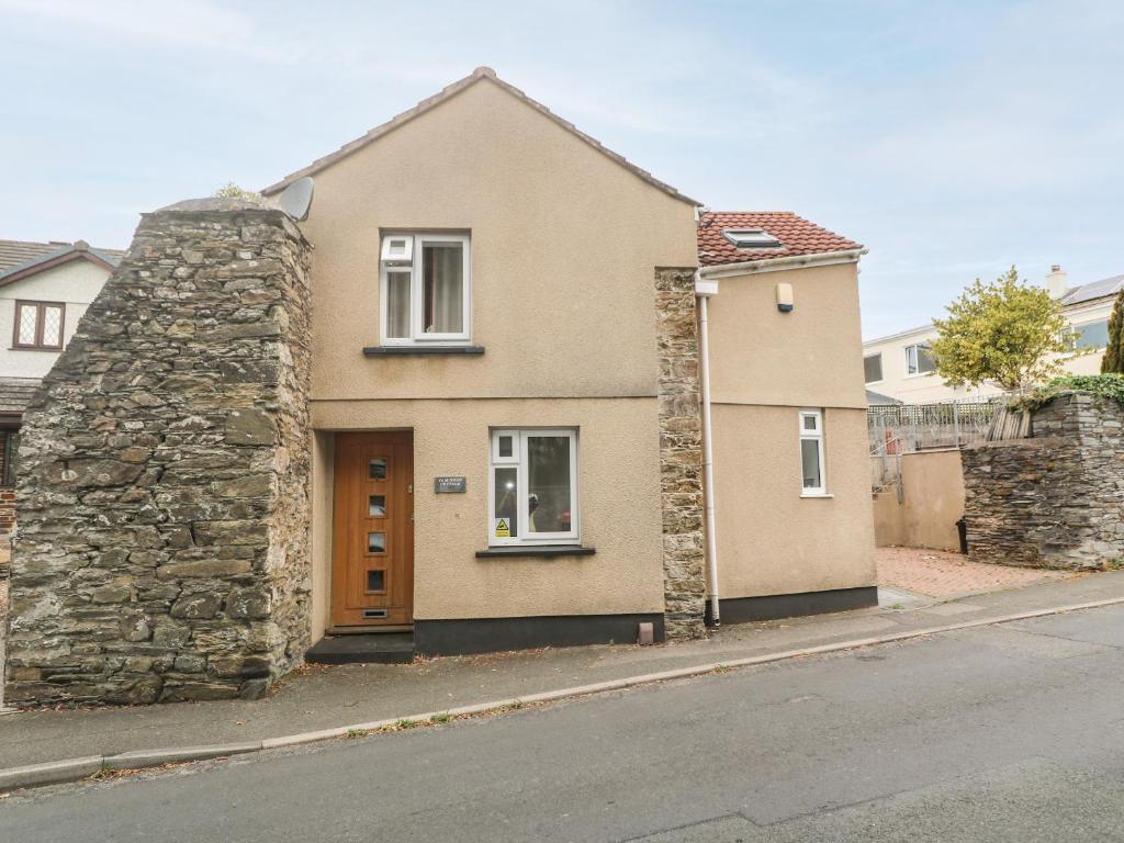 a house with a stone wall next to a street at Fair Mead Cottage in Saltash