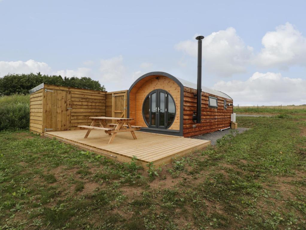 eine kleine Hütte mit einer Holzterrasse auf einem Feld in der Unterkunft Dew Pond in Blagdon