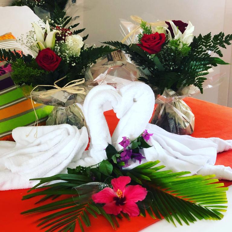 two white swans are sitting on a table with flowers at Hôtel La Christophine in Saint-François