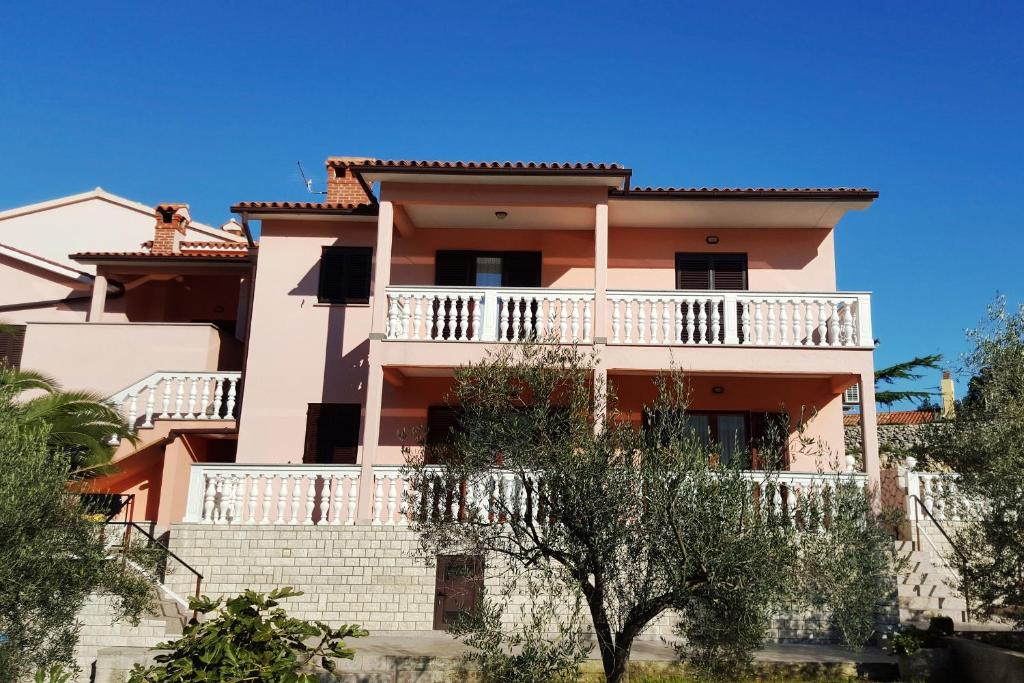 a large pink house with a balcony at Apartments by the sea Duga Luka - Prtlog, Labin - 2358 in Drenje
