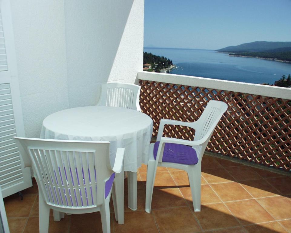 a table and two chairs on a balcony with the ocean at Apartment Rabac 2323a in Rabac