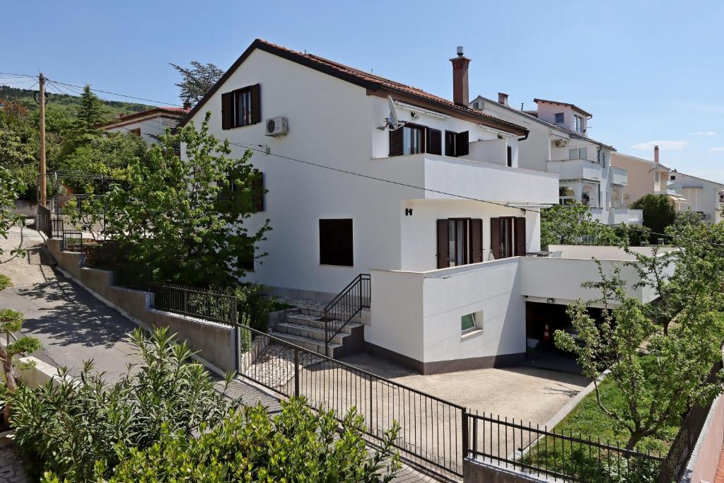 una casa bianca con una recinzione nera e alberi di Apartments and rooms with parking space Selce, Crikvenica - 2362 a Selce