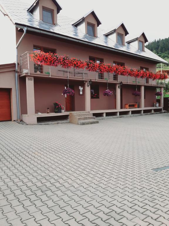 un edificio con flores rojas a un lado. en Penzion Smrek, en Habovka