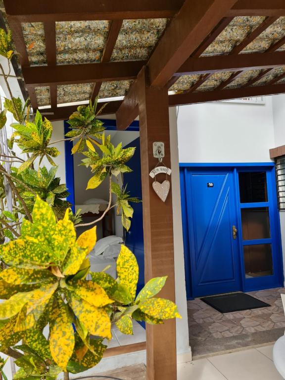 une porte bleue sur une maison avec des plantes dans l'établissement Maika'i Pousada, à Balneário Camboriú