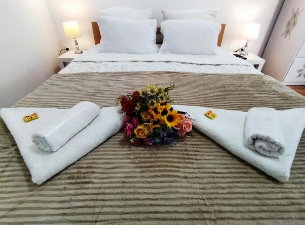 a bed with towels and a bouquet of flowers on it at Palace Luxury Apartments The Heart of Belgrade in Belgrade