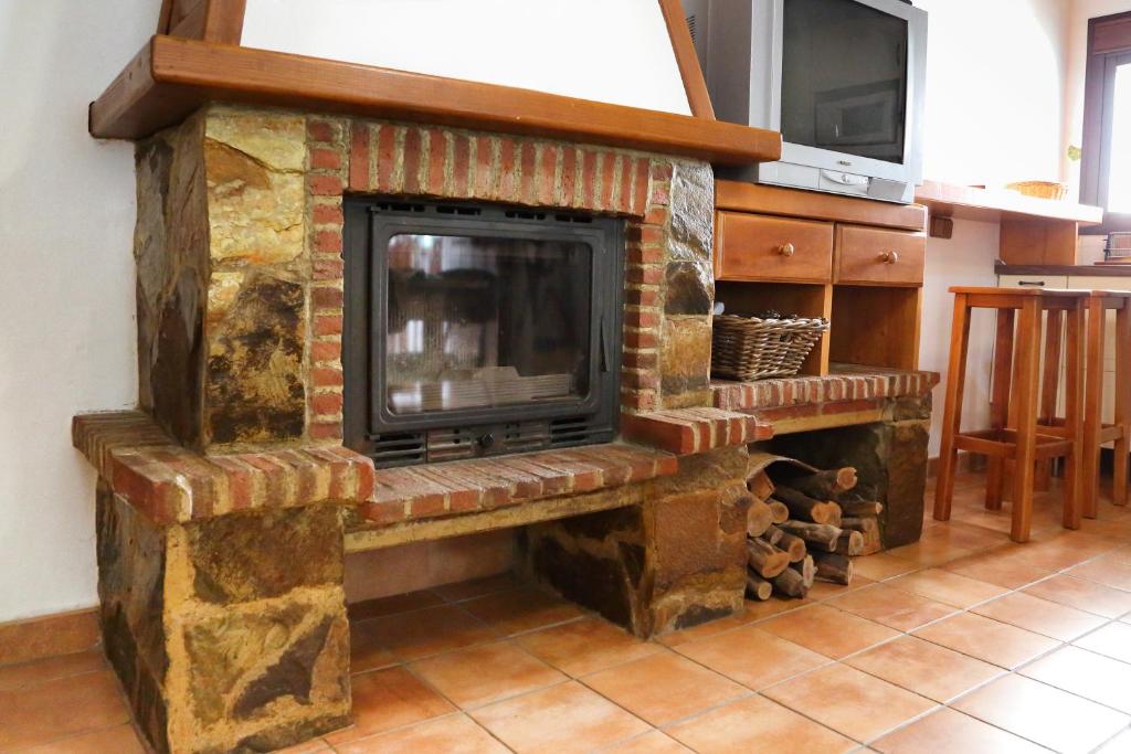 uma lareira de tijolos com uma televisão em cima em casa la parra em Jubrique