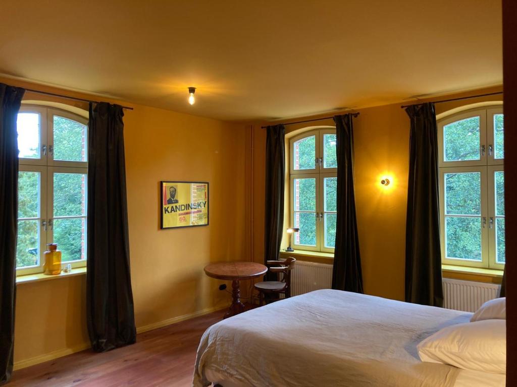 Schlafzimmer mit einem Bett, einem Tisch und Fenstern in der Unterkunft An Den Wiesen Gasthaus am Finowkanal in Wandlitz