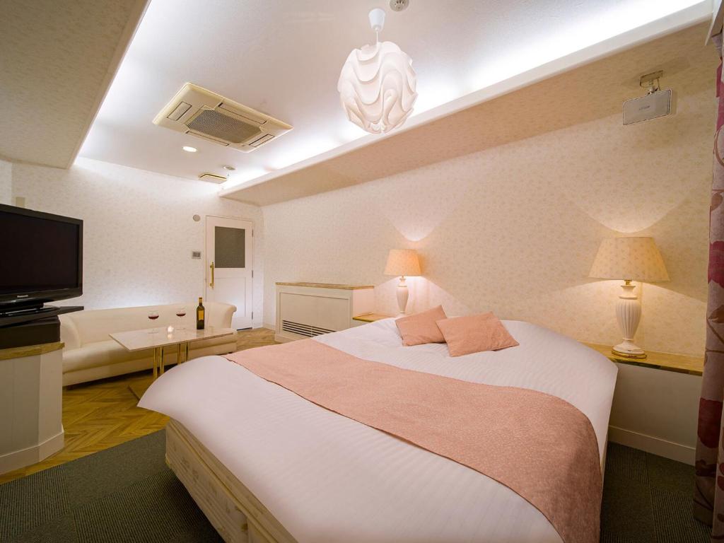 HOTEL U's Kouroen - Vacation STAY 11243v في نيشينومايا: غرفة نوم بسرير كبير وتلفزيون