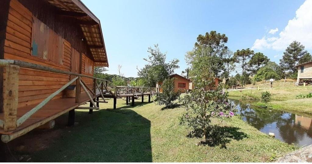 a log cabin with a bridge next to a river at Chalé Caminho da Montanha in Gonçalves