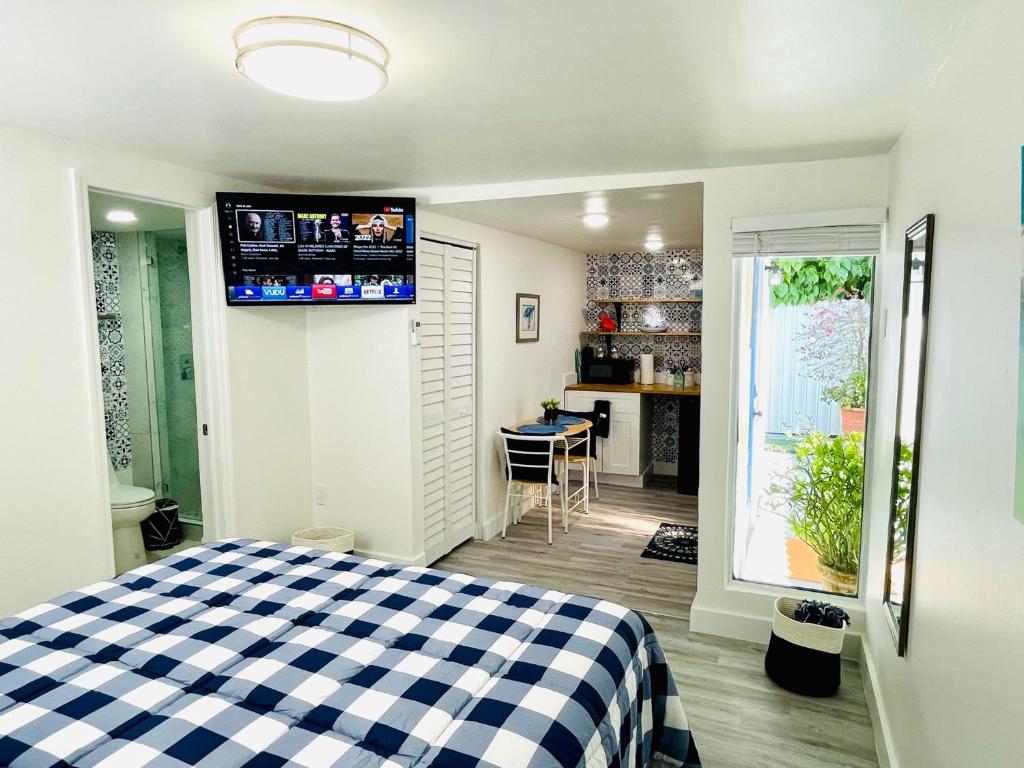 a bedroom with a checkered bed and a kitchen at Our Lovely Nest, Free Parking & Wi-Fi in Miami