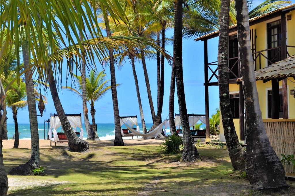 a resort with palm trees and a hammock on the beach at Rumah Pousada in Barra Grande