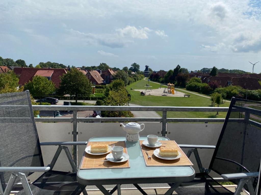 una mesa con 2 platos de comida en el balcón en FeWo Herzstück - Neßmersiel en Neßmersiel