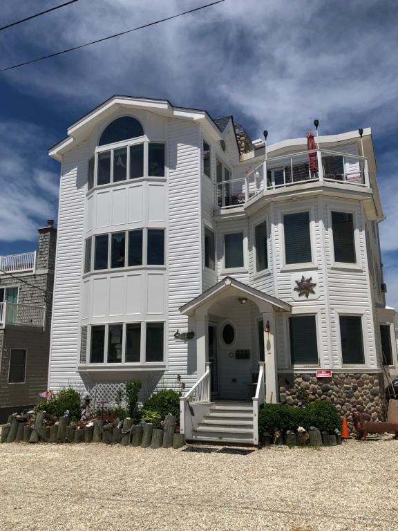 Beach Haven Crest的住宿－Beach House Retreats 6-just 30 Steps from the Beach with Rooftop Hot Tub and Gourmet Kitchen，一座大型白色房子,上面设有门廊