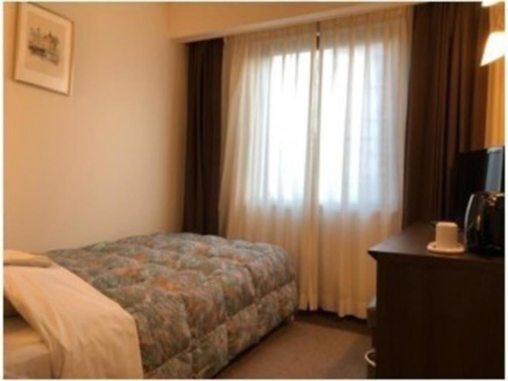ein Schlafzimmer mit einem Bett und einem Fenster mit Vorhängen in der Unterkunft Grand Plaza Nakatsu Hotel - Vacation STAY 28275v in Nakatsu