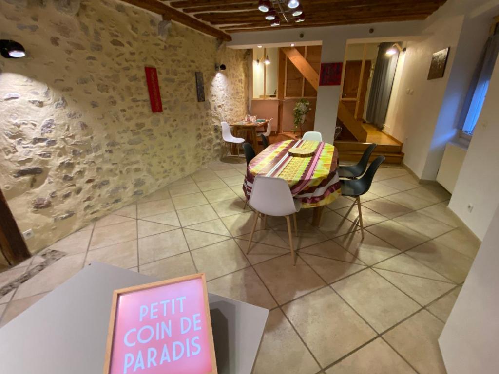 a table and chairs in a room with a sign at Gîte de la tour de Paradis in Poligny