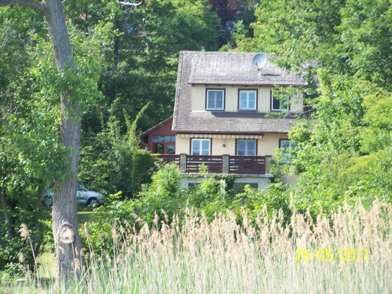 ein Haus an der Seite eines Hügels mit Bäumen in der Unterkunft Ferienhaus Haus am Ufer in Gaienhofen