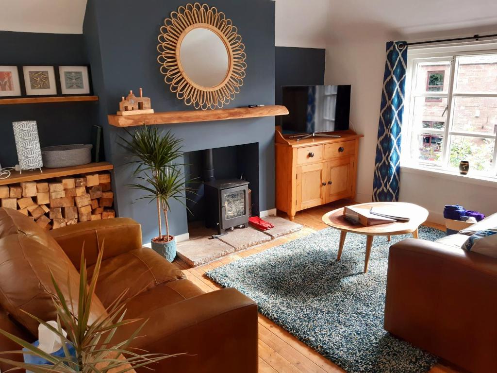 a living room with a couch and a fireplace at The Burnside Apartment in Fettercairn