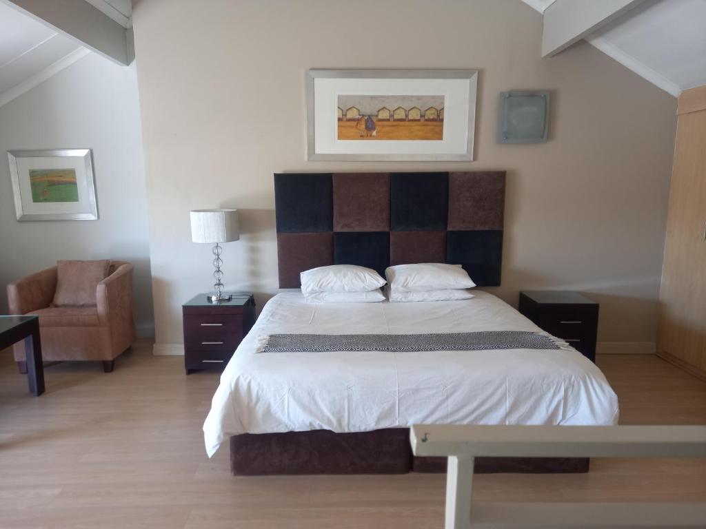 ein Schlafzimmer mit einem großen Bett und einem Stuhl in der Unterkunft Mount Royal 31 - Large 1 bed with balcony in Johannesburg