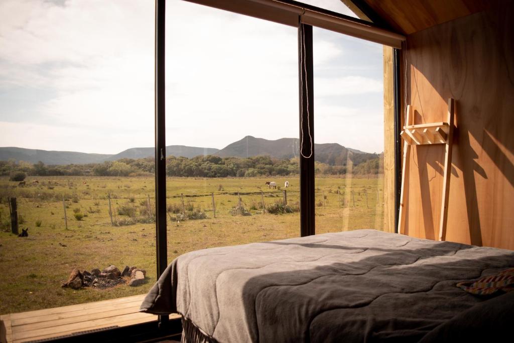 a bedroom with a large window with a view of a field at Villa Pancha del Lunarejo in Sierra de Lunarejo