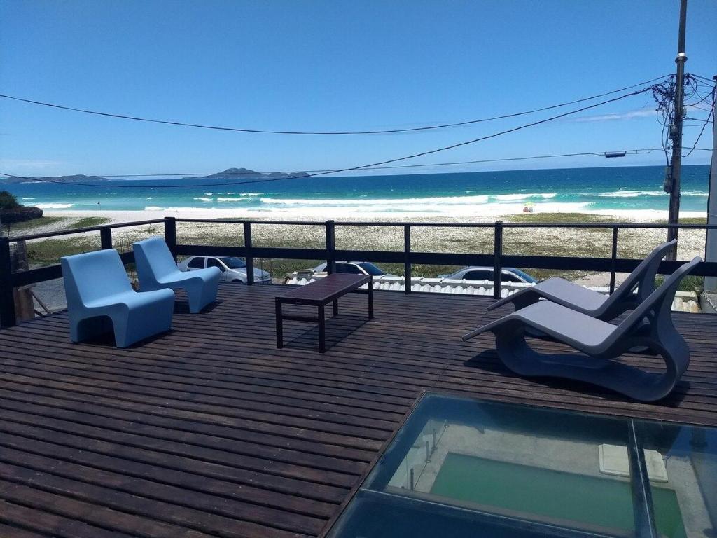 um deque com cadeiras e uma piscina e a praia em Casa do Beiral Azul 5 Qts Pé na areia Piscina em Cabo Frio