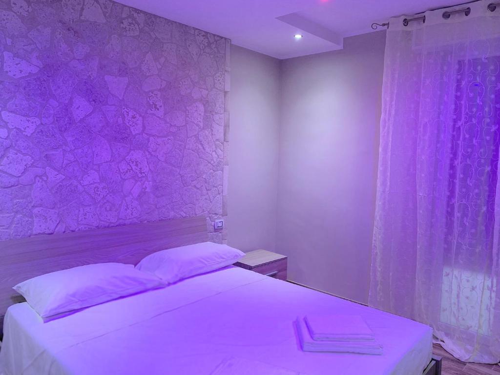 a bedroom with a white bed with a purple wall at B&B New Paris & Suite in Taranto
