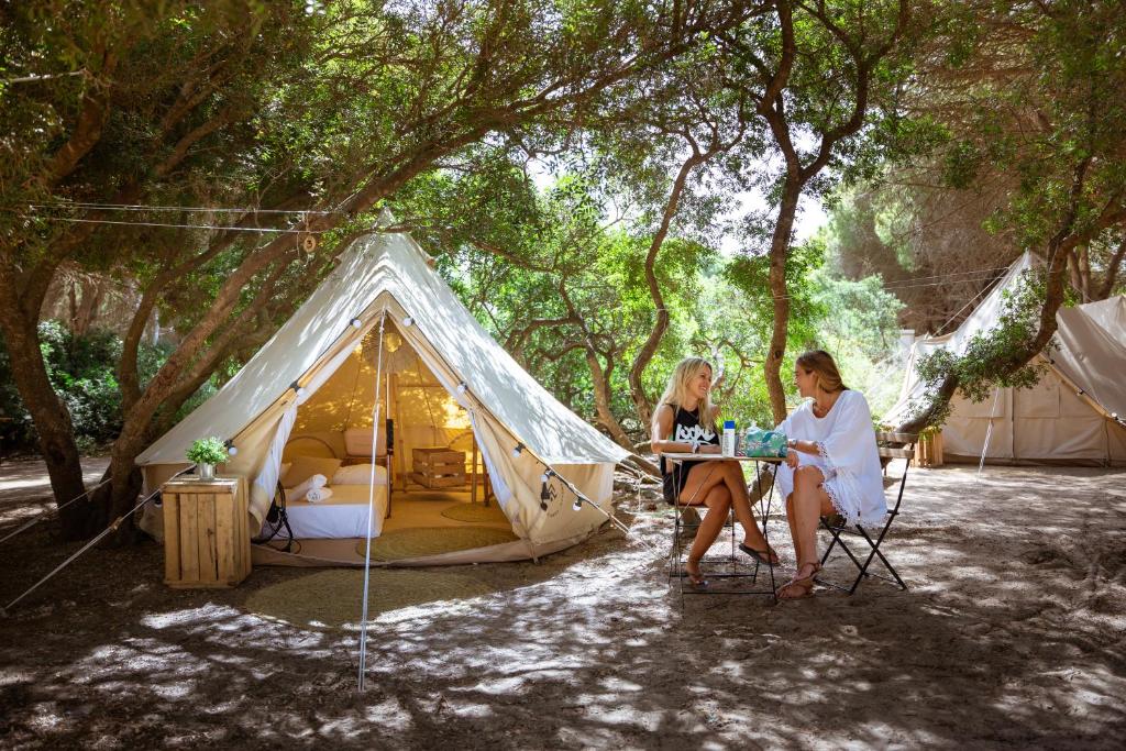 Due donne sedute a un tavolo di fronte a una tenda di Kampaoh Los Caños a Los Caños de Meca