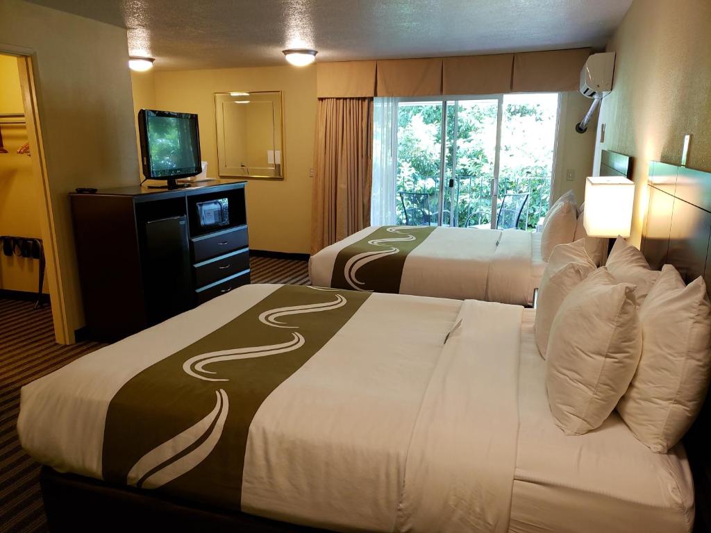 a hotel room with two beds and a flat screen tv at Quality Inn & Suites in Vancouver